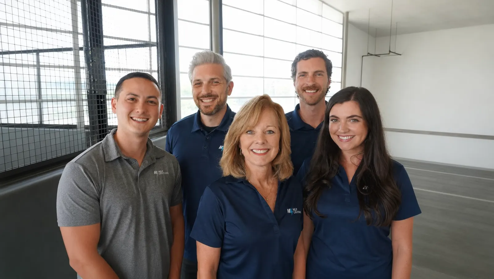 Five Help Lightning teammates in company polos, smiling in a bright office.