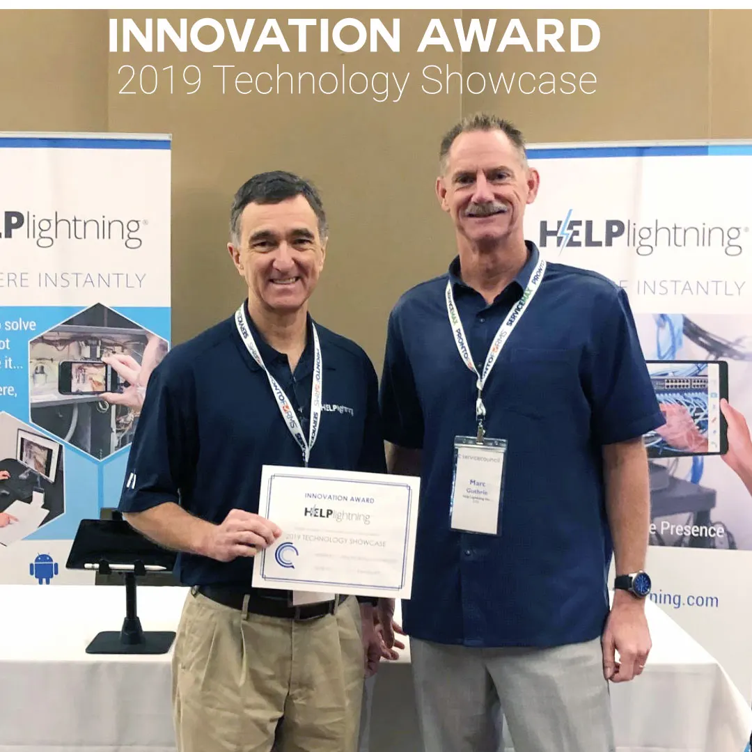 Two teammates holding a 2019 Technology Showcase Innovation Award certificate at a Help Lightning booth.