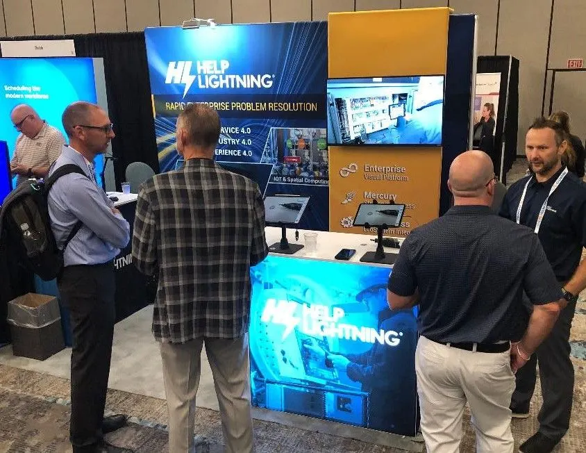 Visitors and a Help Lightning representative talking at a trade-show booth with demo tablets.